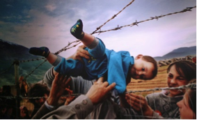 child being lifted by adults through a fence